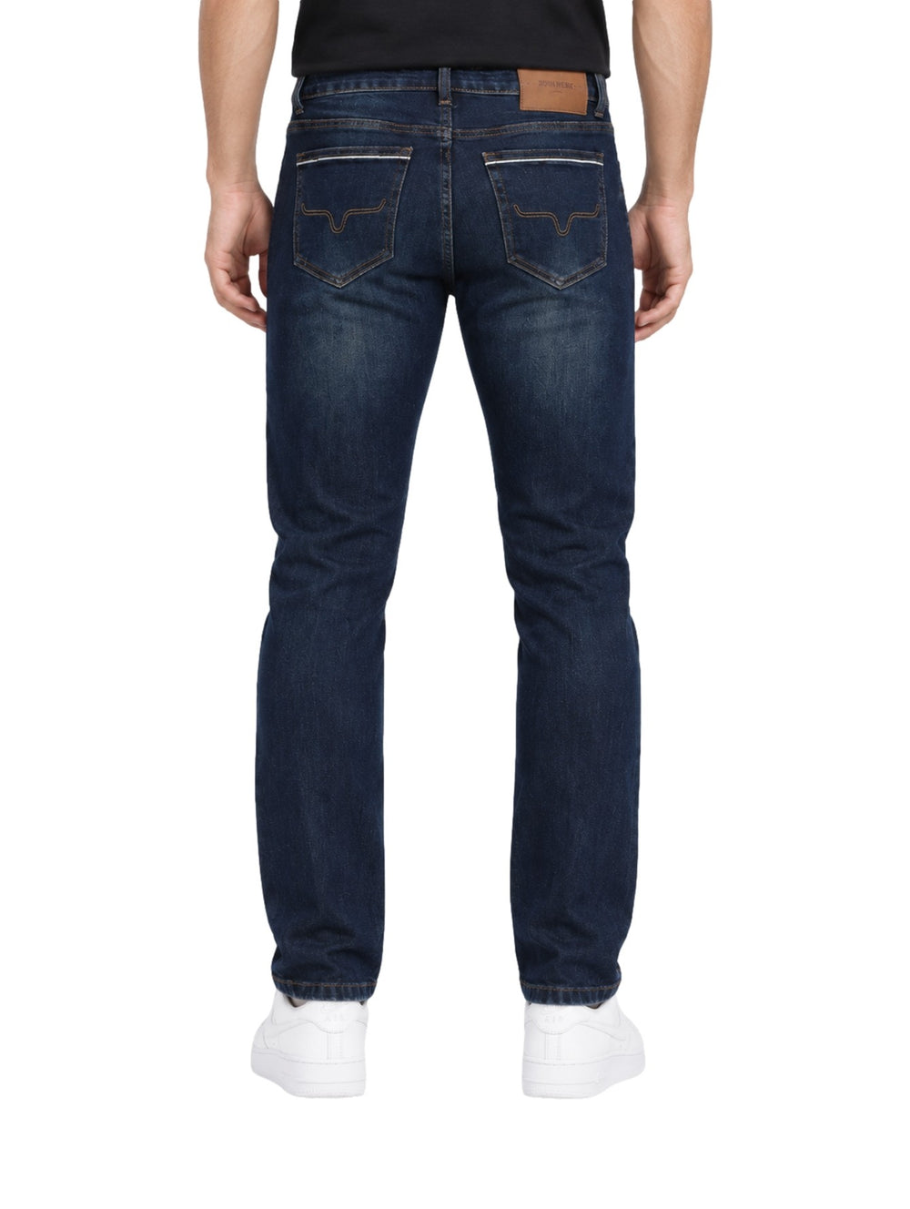 Hombre vistiendo jeans rectos de color índigo con calzado blanco sobre fondo blanco.