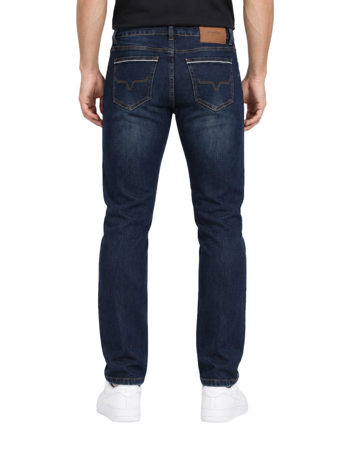 Hombre vistiendo jeans rectos de color índigo con calzado blanco sobre fondo blanco.
