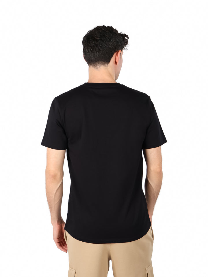 Hombre vistiendo una camiseta negra de manga corta con el logo DKNY en el pecho.