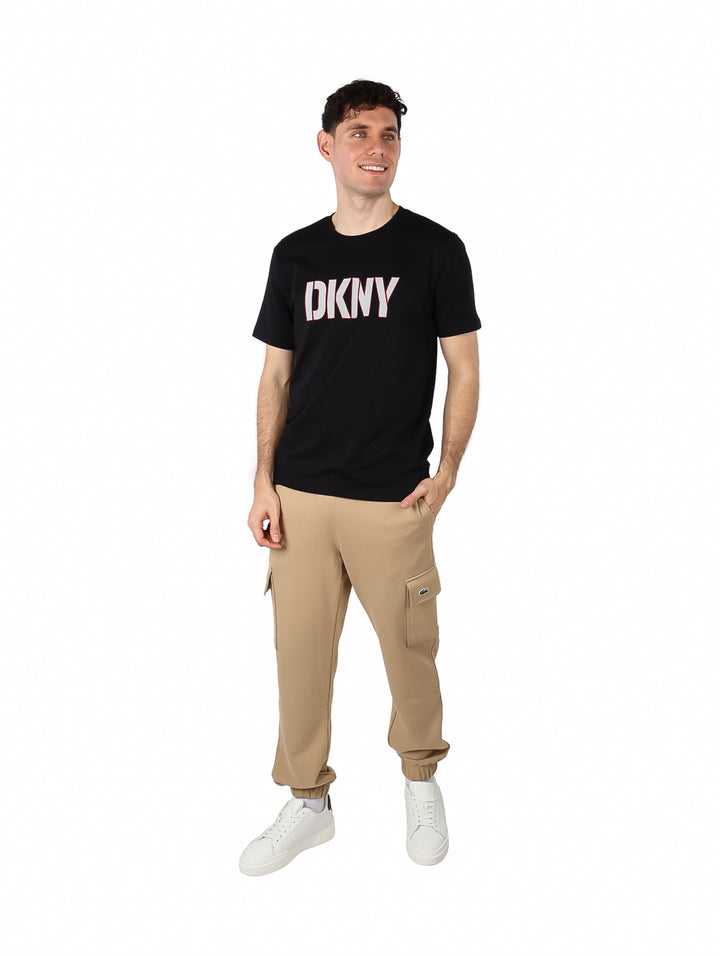 Hombre vistiendo una camiseta negra de manga corta con el logo DKNY en el pecho.