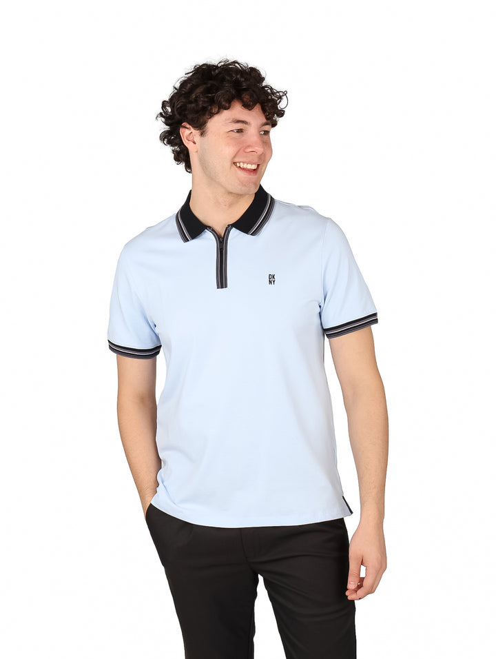 Hombre vistiendo una playera polo color azul claro con detalles en negro en el cuello y mangas.