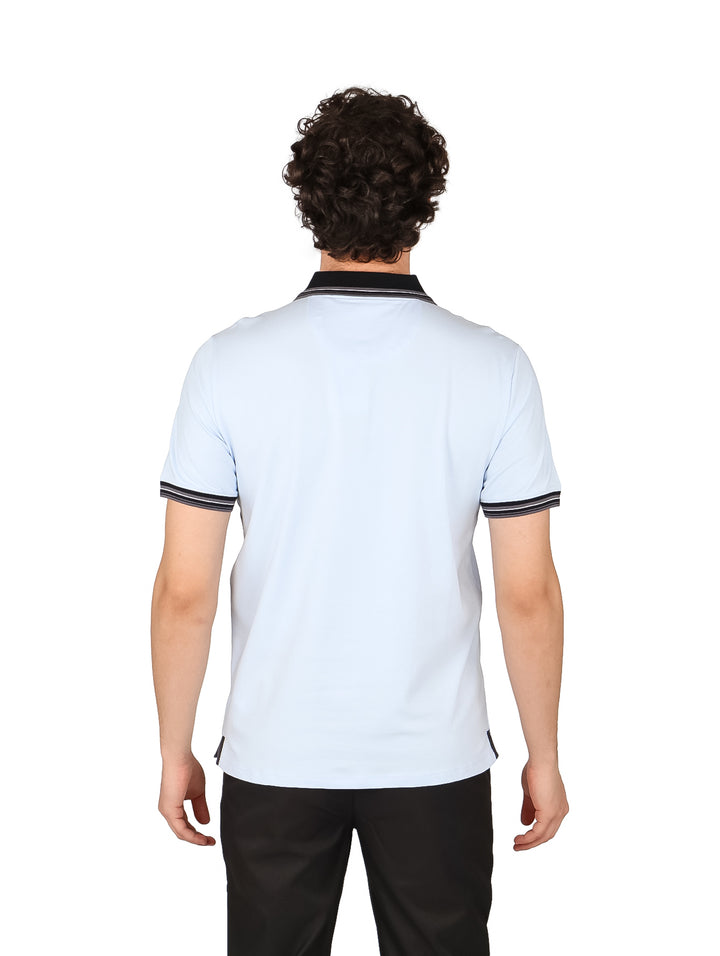 Hombre vistiendo una playera polo color azul claro con detalles en negro en el cuello y mangas.