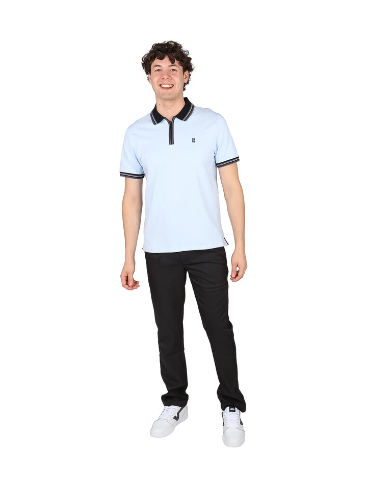 Hombre vistiendo una playera polo color azul claro con detalles en negro en el cuello y mangas.
