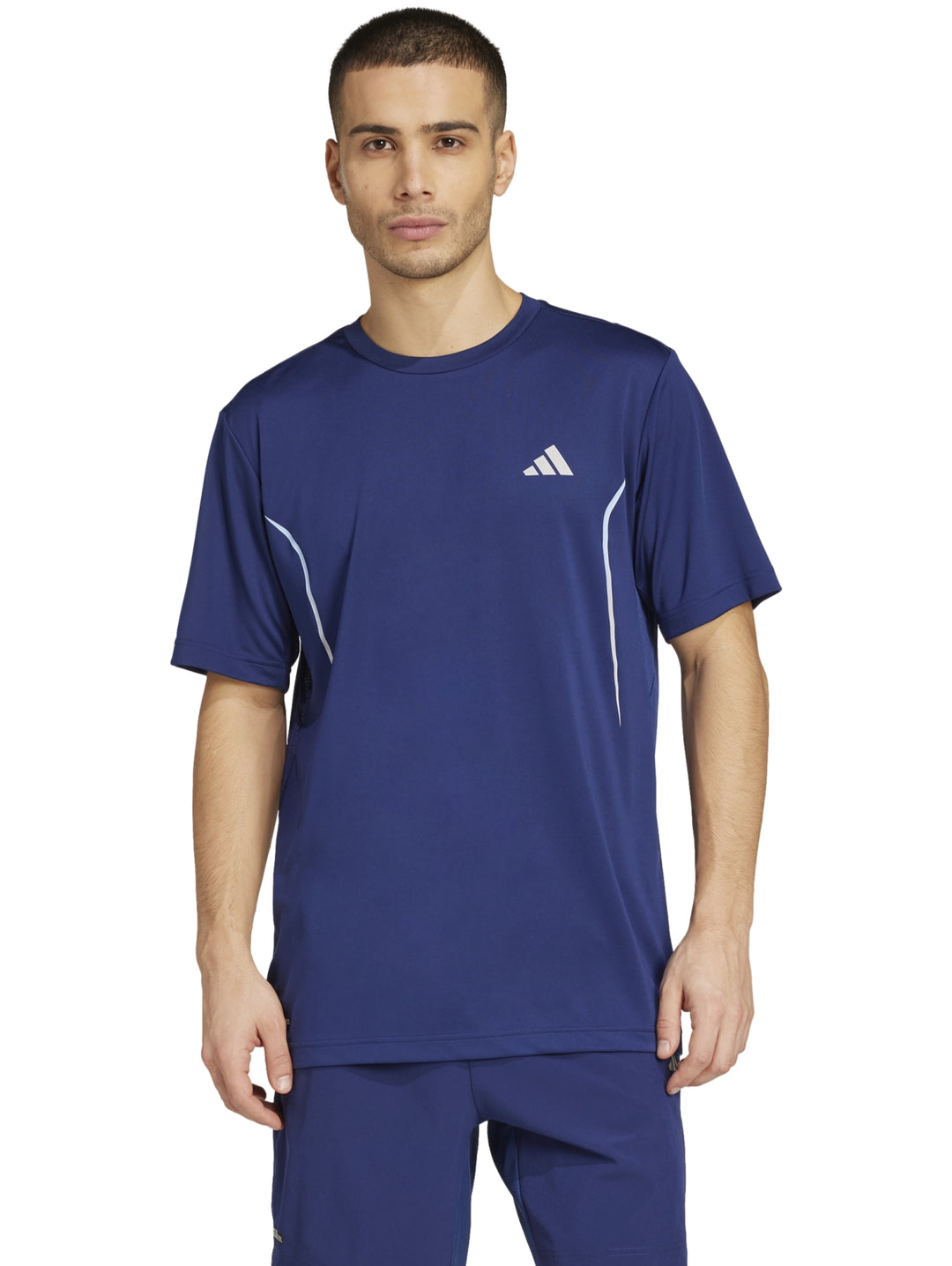 Hombre vistiendo una camiseta deportiva Adidas de color azul oscuro con detalles reflectantes laterales.