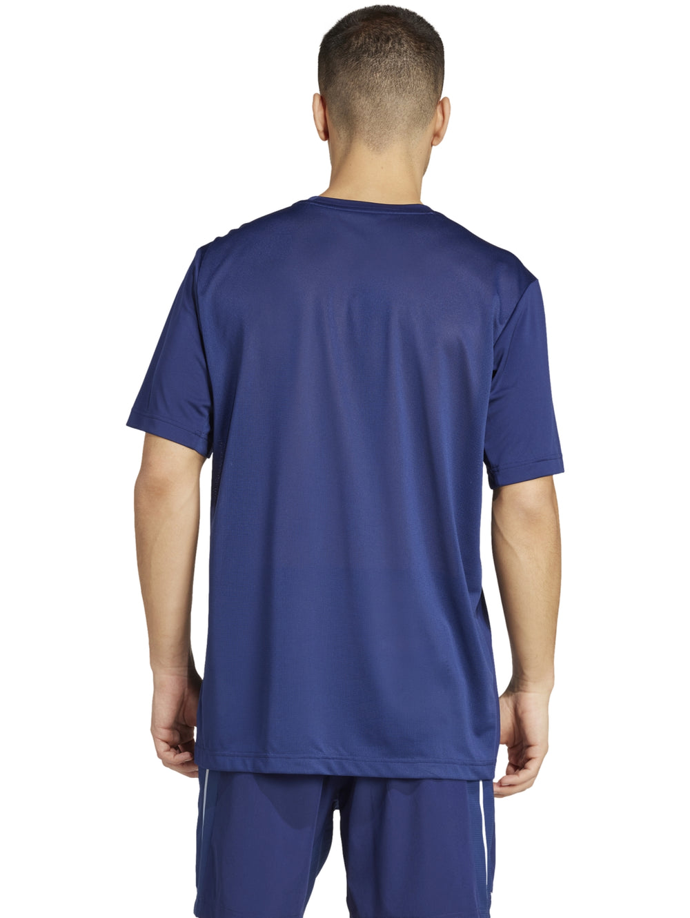 Hombre vistiendo una camiseta deportiva Adidas de color azul oscuro con detalles reflectantes laterales.