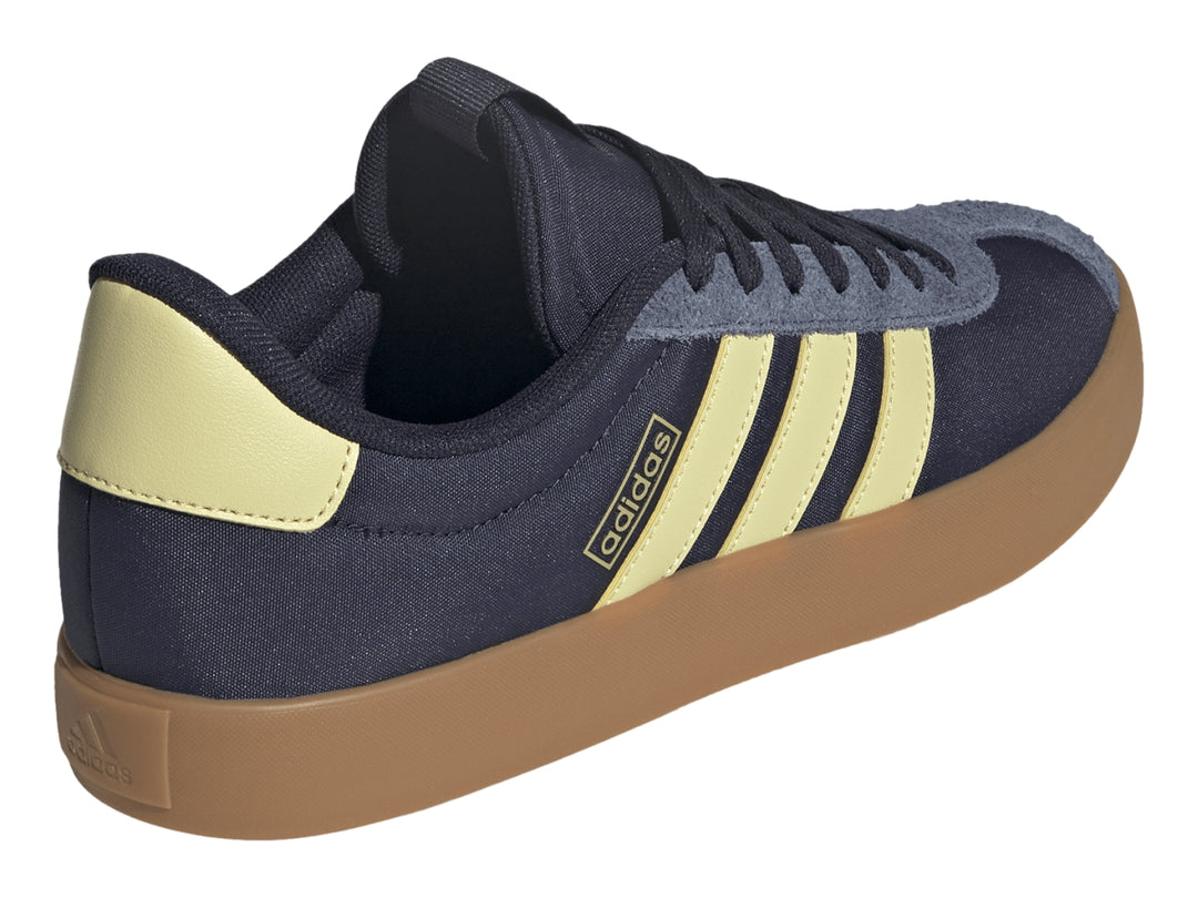Tenis Adidas VL Court 3.0 color azul marino con franjas amarillas y suela de goma color café.