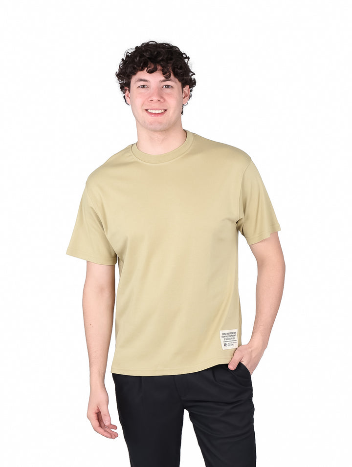 Hombre vistiendo una playera de manga corta color beige con cuello redondo.