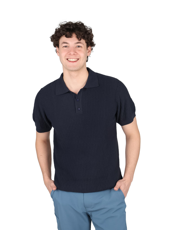 Hombre vistiendo una playera polo de color azul marino con cuello y botones.