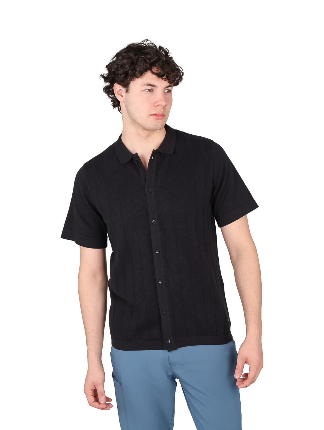 Hombre vistiendo una playera polo de color negro con botones frontales y manga corta.