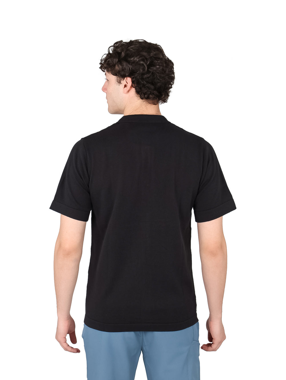 Hombre vistiendo una playera polo de color negro con botones frontales y manga corta.