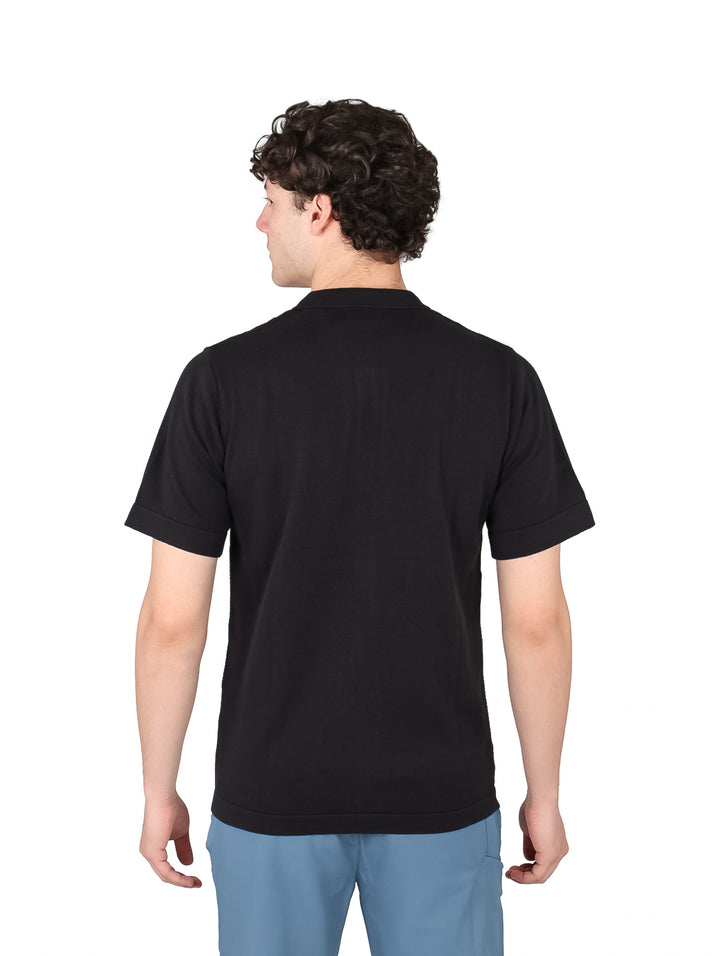 Hombre vistiendo una playera polo de color negro con botones frontales y manga corta.