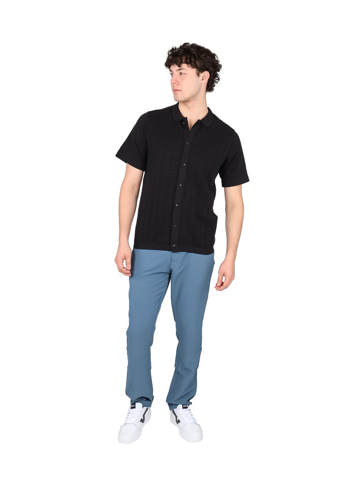 Hombre vistiendo una playera polo de color negro con botones frontales y manga corta.