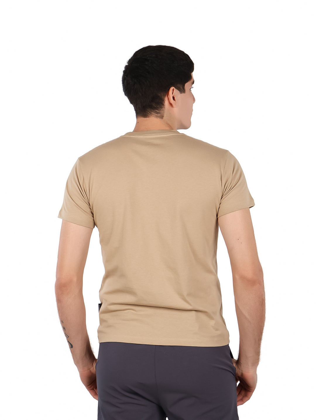 Hombre vistiendo una playera color beige con cuello redondo y texto &