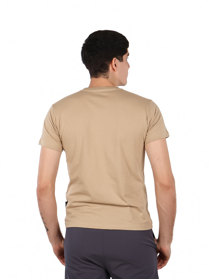 Hombre vistiendo una playera color beige con cuello redondo y texto &