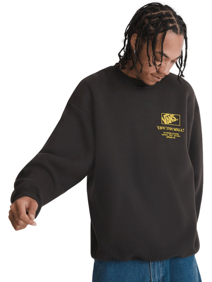 Hombre vistiendo una sudadera negra de cuello redondo con logotipo amarillo de VANS en el pecho.