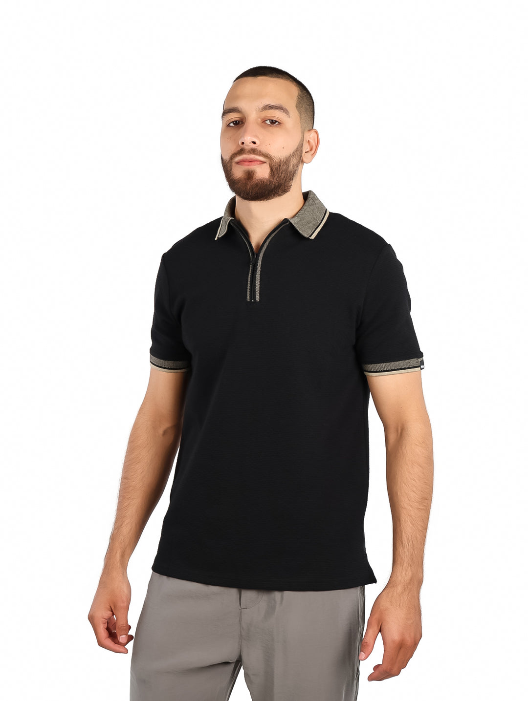 Hombre vistiendo playera polo negra de manga corta con detalles grises en el cuello y puños.