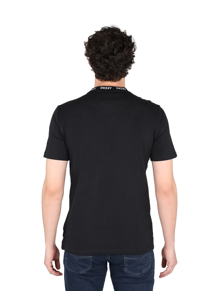 Hombre vistiendo camiseta negra de manga corta DKNY con logotipo blanco en el cuello y pecho.