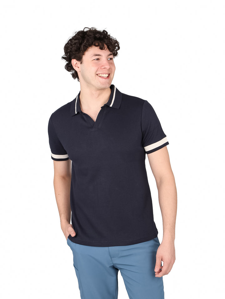 Hombre vistiendo una playera polo color azul marino con detalles en blanco en mangas y cuello.