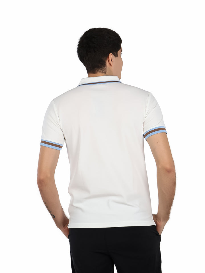 Hombre vistiendo playera polo blanca con detalles de rayas azules y cafés en cuello y mangas.