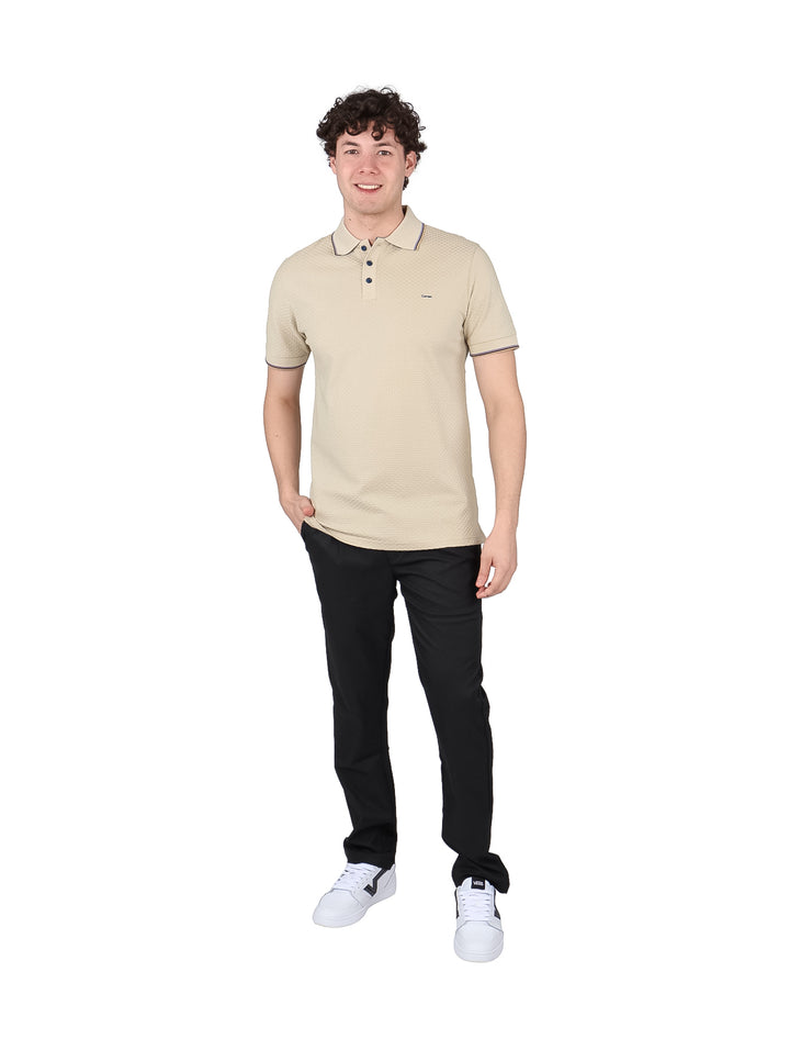 Hombre vistiendo playera polo color sand con textura y detalles en azul marino en cuello y mangas.