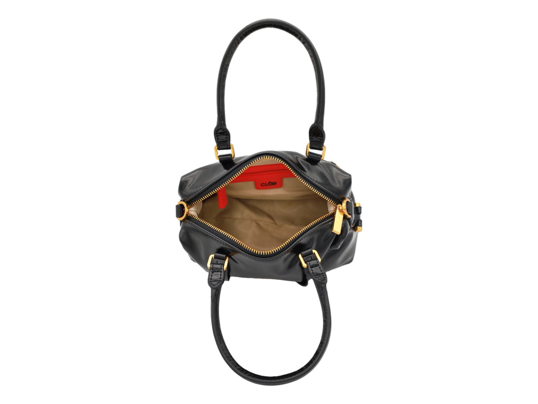 Bolso de mano Cloe color negro brillante con herrajes y logotipo en tono dorado.