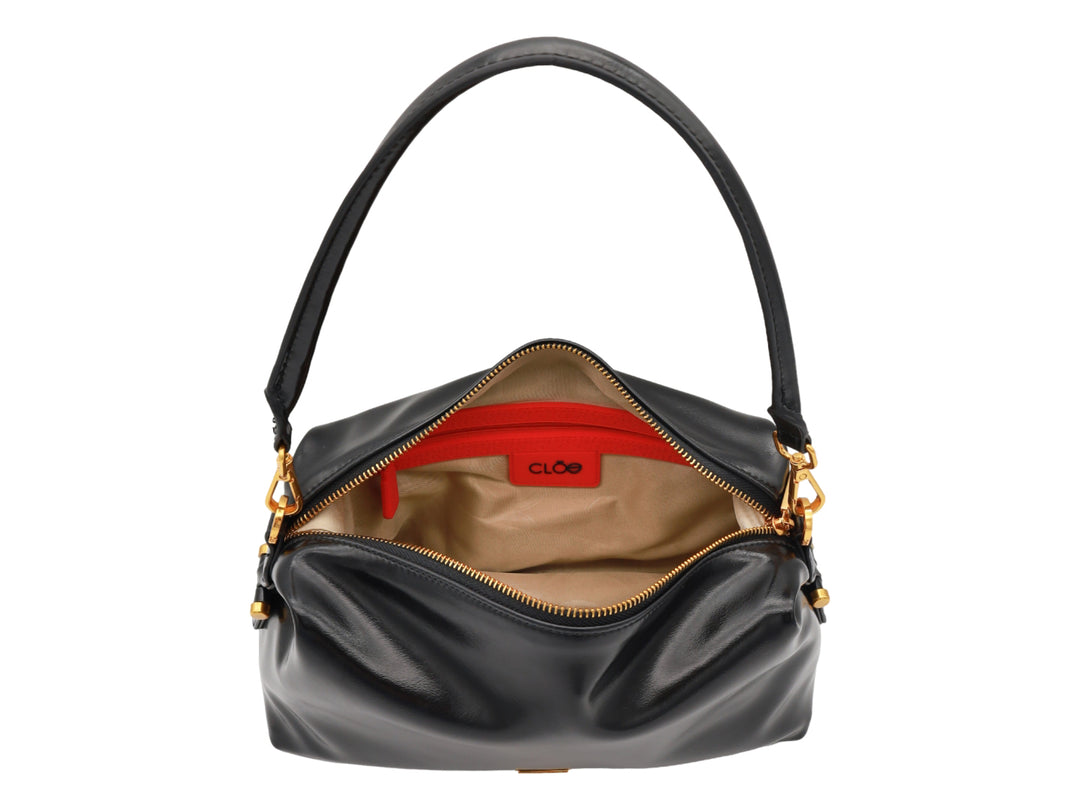 Bolso Cloe color negro con herrajes dorados, asa corta y correa larga ajustable.