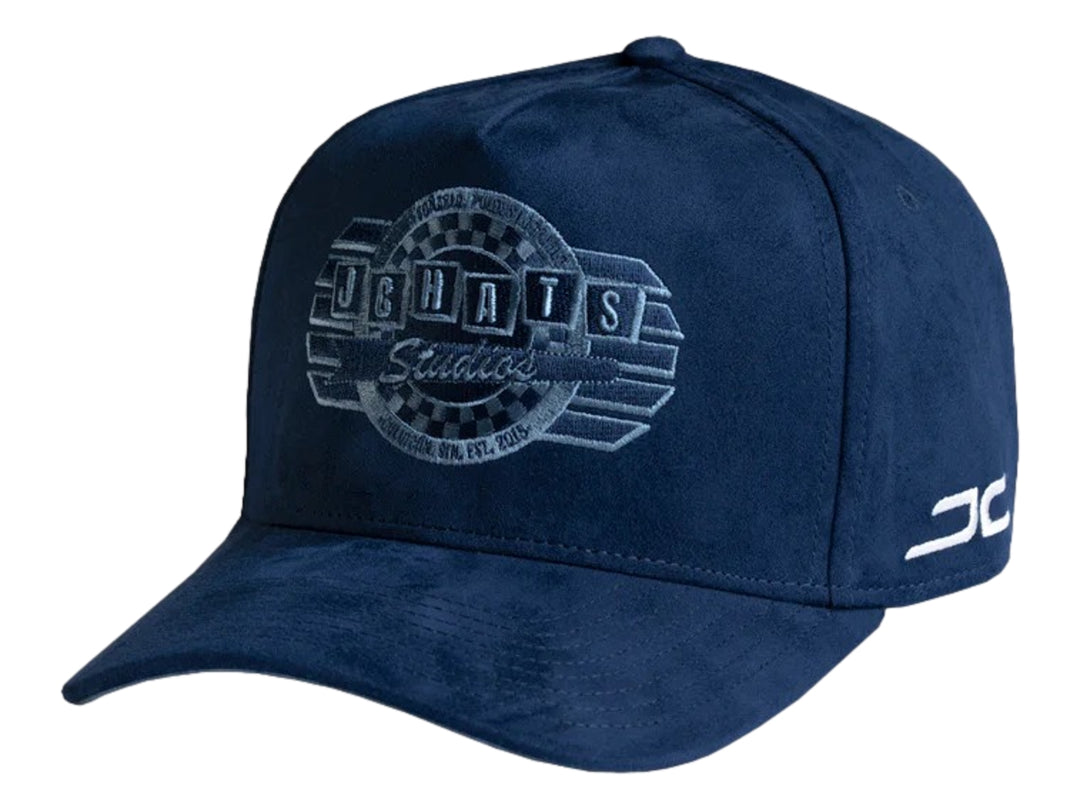 Gorra snapback color azul marino con logotipo bordado de JC HATS Studios en el frente y lateral.