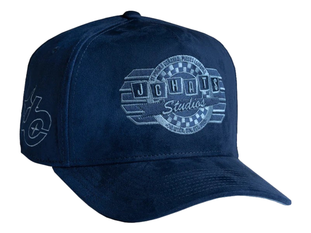 Gorra snapback color azul marino con logotipo bordado de JC HATS Studios en el frente y lateral.