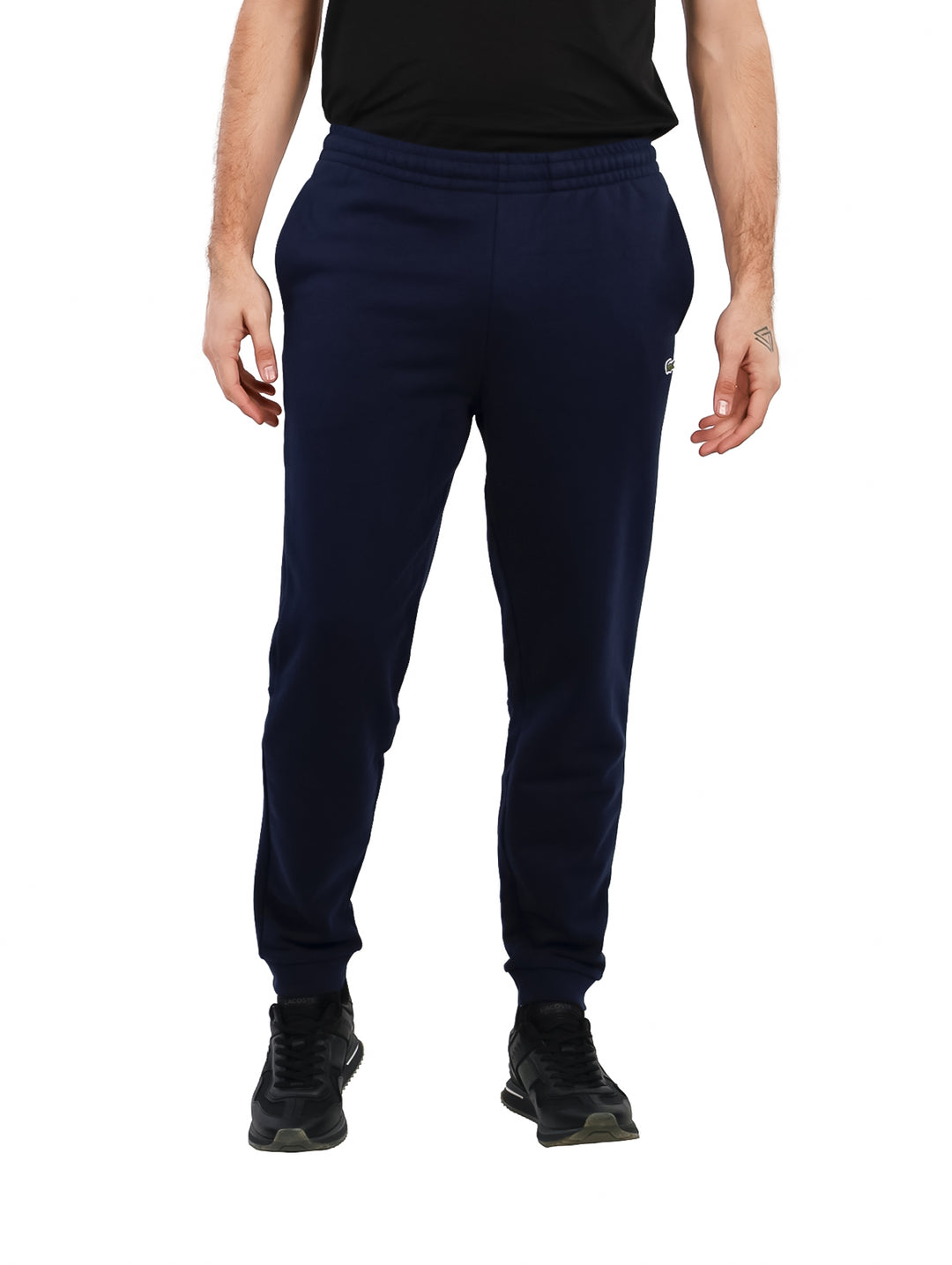 Hombre vistiendo pantalones deportivos Lacoste en color azul marino con corte tapered fit.