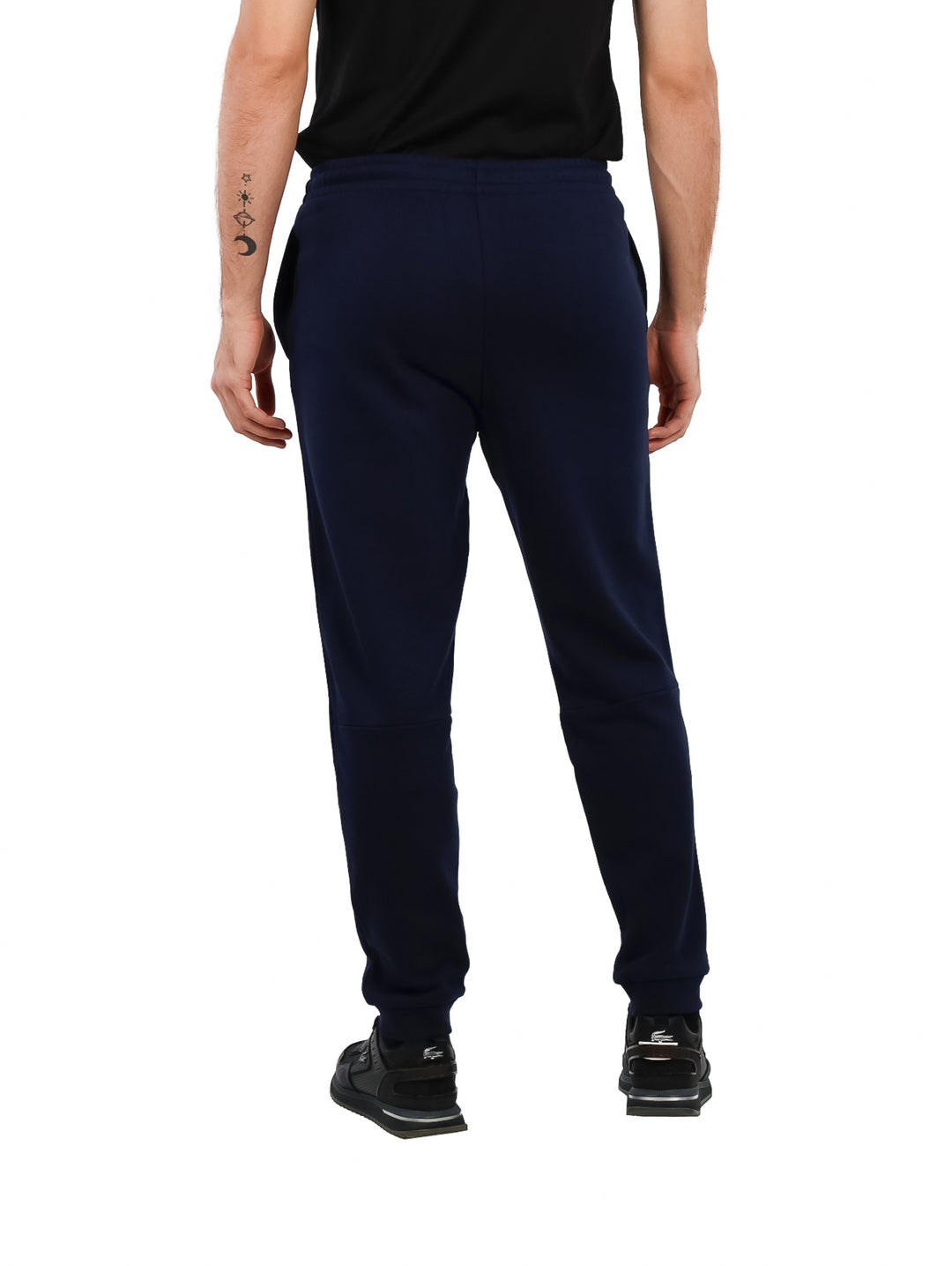 Hombre vistiendo pantalones deportivos Lacoste en color azul marino con corte tapered fit.