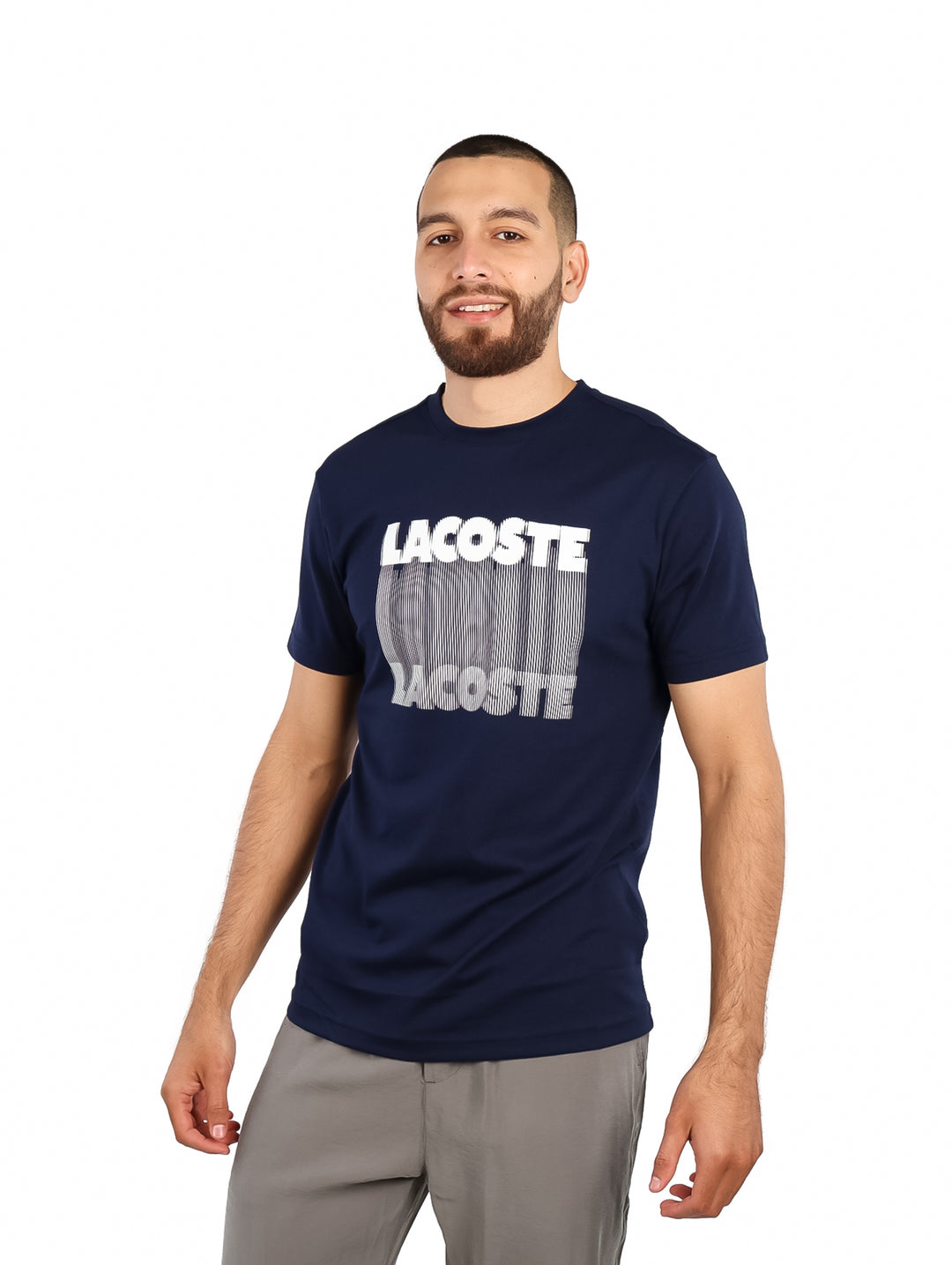 Hombre vistiendo una camiseta de manga corta color azul marino con estampado blanco de la marca Lacoste en el pecho.