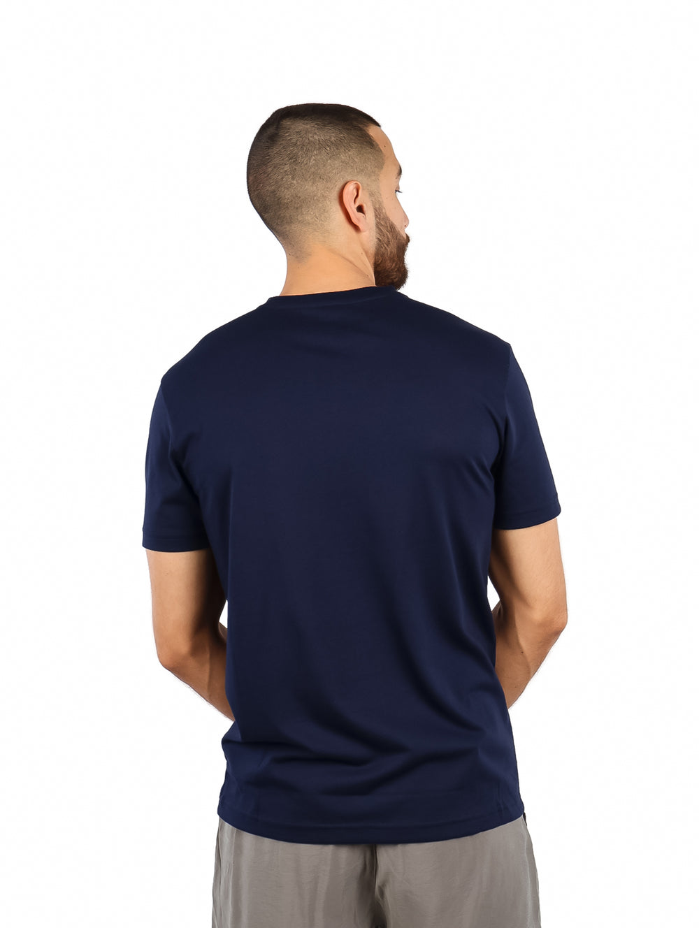 Hombre vistiendo una camiseta de manga corta color azul marino con estampado blanco de la marca Lacoste en el pecho.