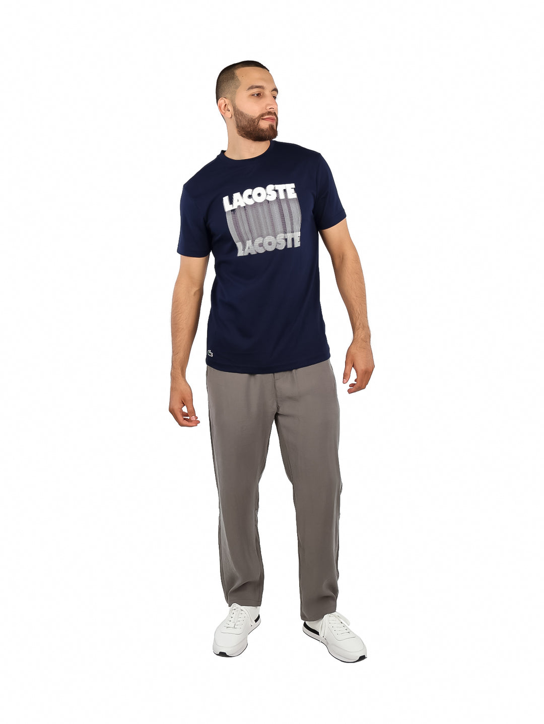Hombre vistiendo una camiseta de manga corta color azul marino con estampado blanco de la marca Lacoste en el pecho.