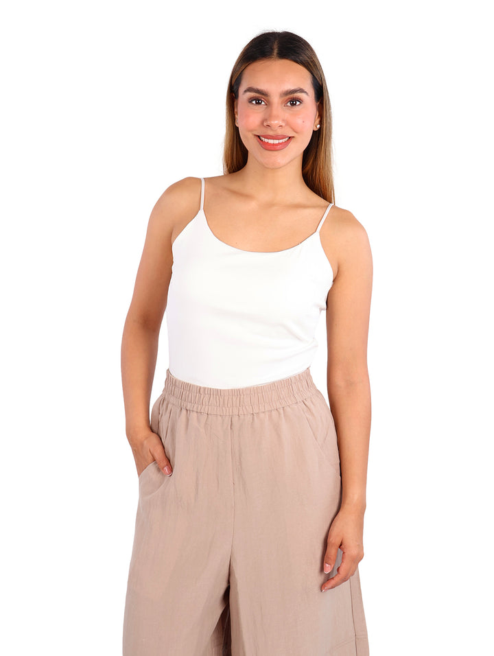 Mujer vistiendo una blusa blanca de tirantes ajustada y pantalones beige.