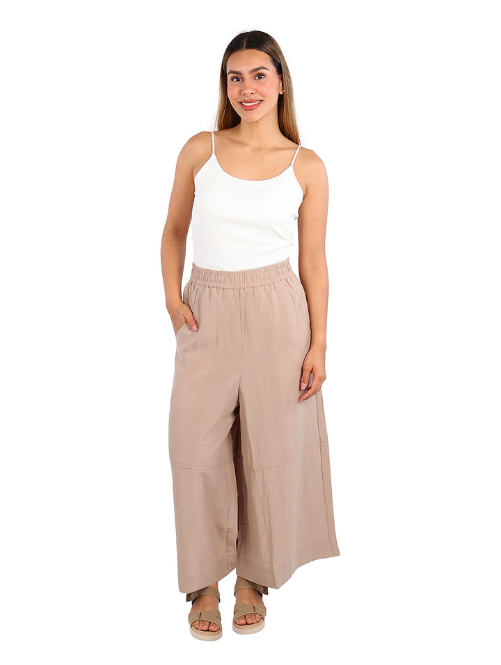 Mujer vistiendo una blusa blanca de tirantes ajustada y pantalones beige.