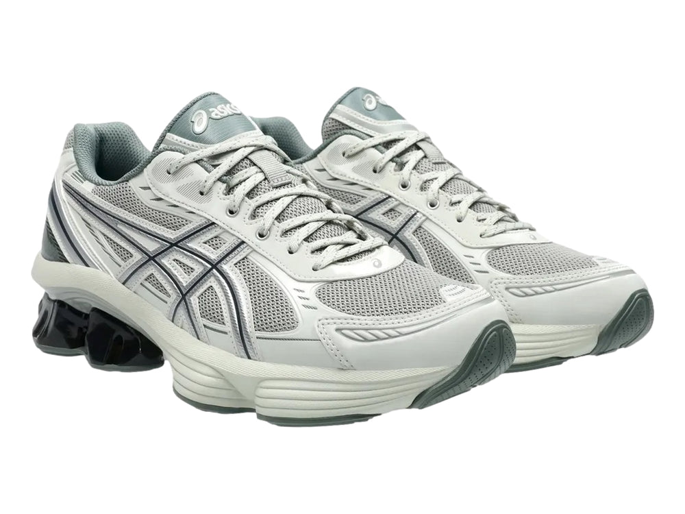 Tenis deportivos ASICS color gris y plata con suela blanca y detalle negro brillante en el talón.