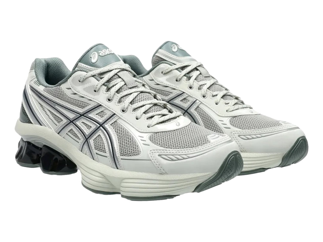 Tenis deportivos ASICS color gris y plata con suela blanca y detalle negro brillante en el talón.