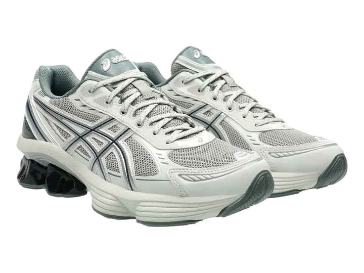 Tenis deportivos ASICS color gris y plata con suela blanca y detalle negro brillante en el talón.