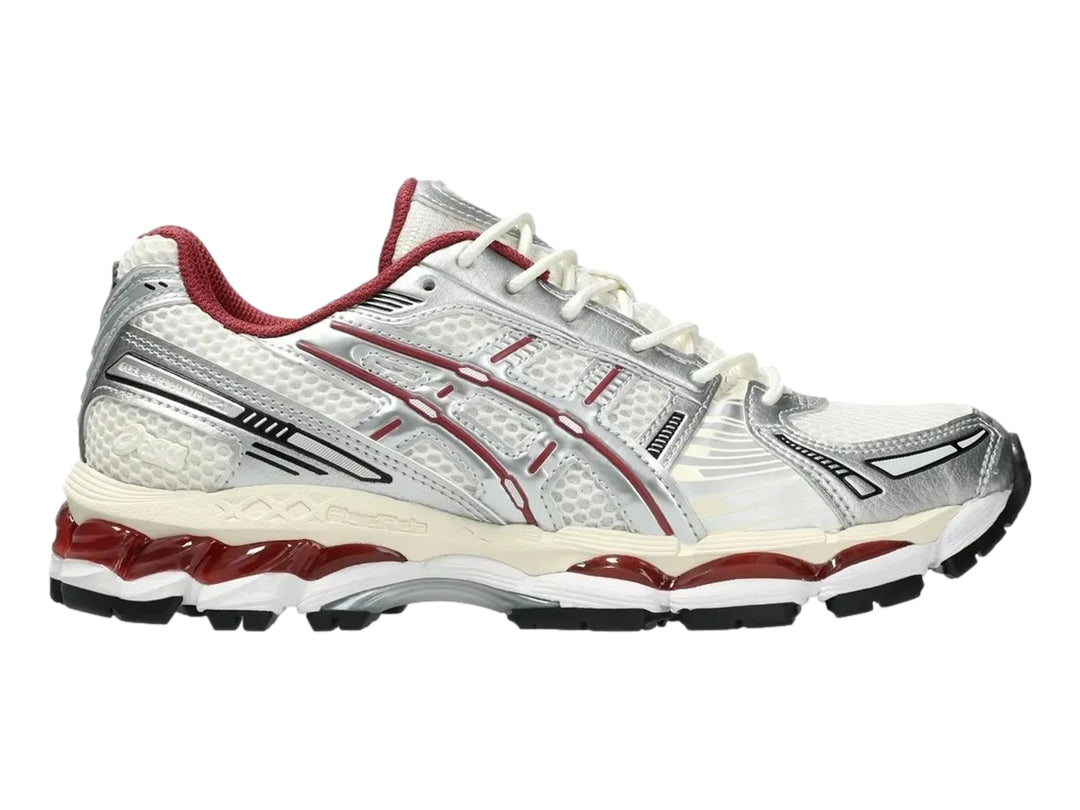 Tenis deportivos ASICS Gel-Kayano 12.1 en colores crema y plata con detalles en rojo y suela negra.