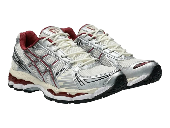 Tenis deportivos ASICS Gel-Kayano 12.1 en colores crema y plata con detalles en rojo y suela negra.