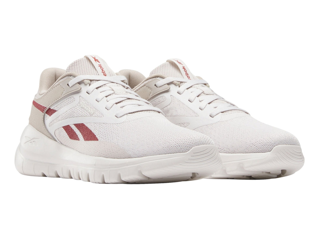 Tenis deportivos Reebok color gris claro con detalles rojos y suela blanca.