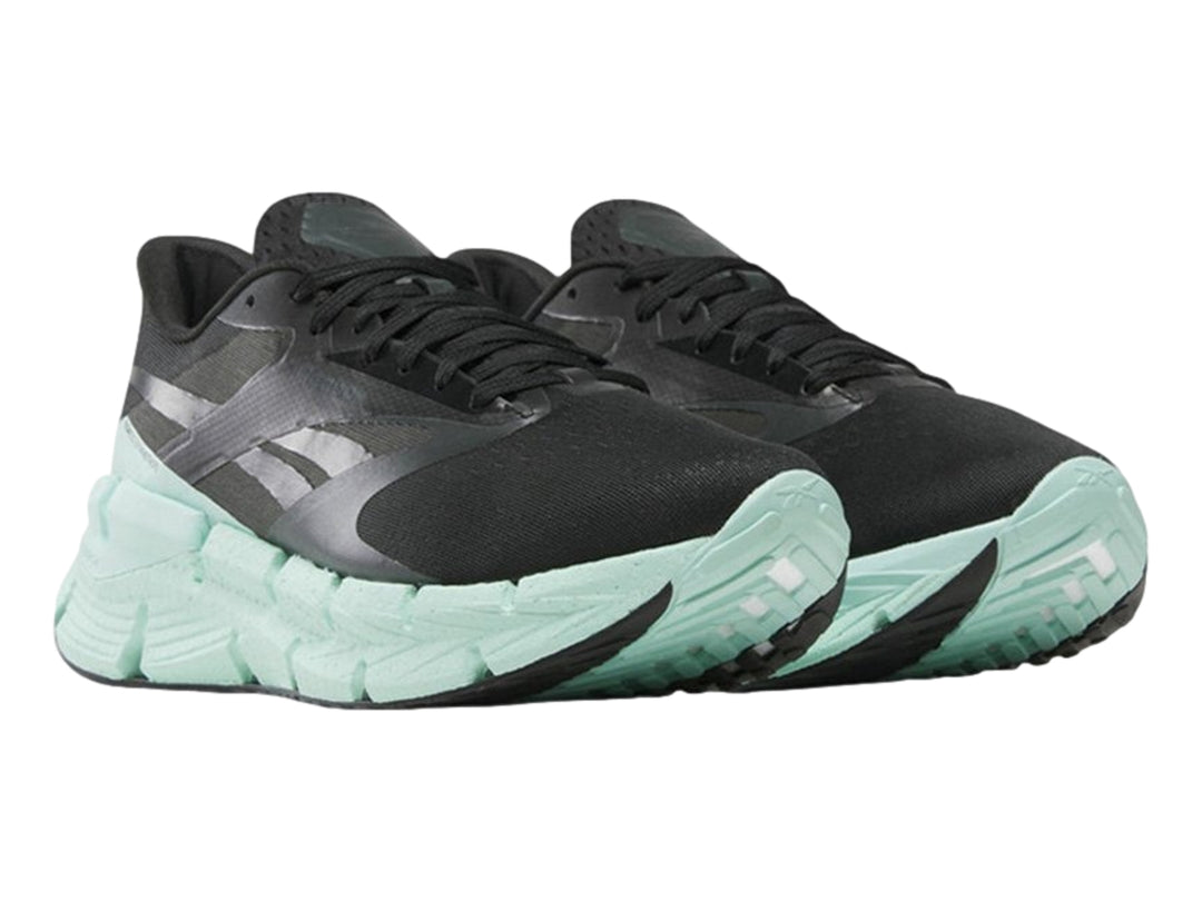 Tenis deportivos Reebok color negro con suela ancha en color verde menta.