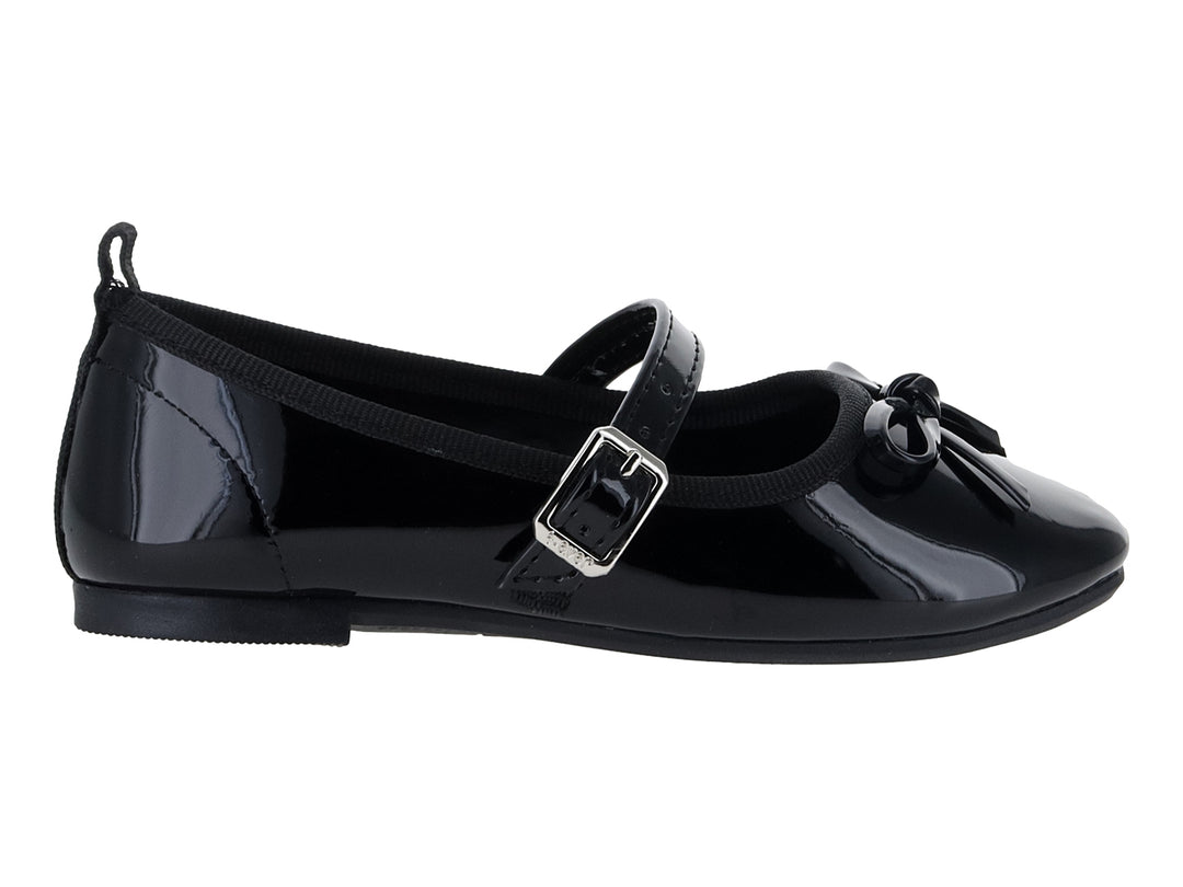 Zapato plano de charol negro con correa, hebilla plateada y moño decorativo.