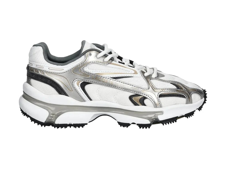 Tenis deportivos Lacoste color blanco y plateado con suela gruesa y diseño moderno.