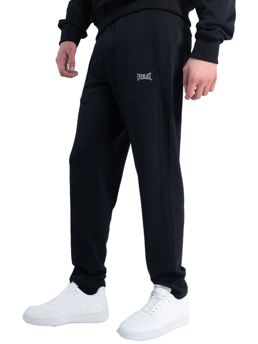 Hombre vistiendo un pantalón deportivo Everlast de color negro con calzado blanco sobre fondo blanco.