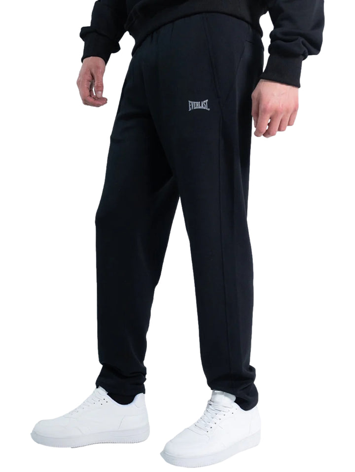 Hombre vistiendo un pantalón deportivo Everlast de color negro con calzado blanco sobre fondo blanco.