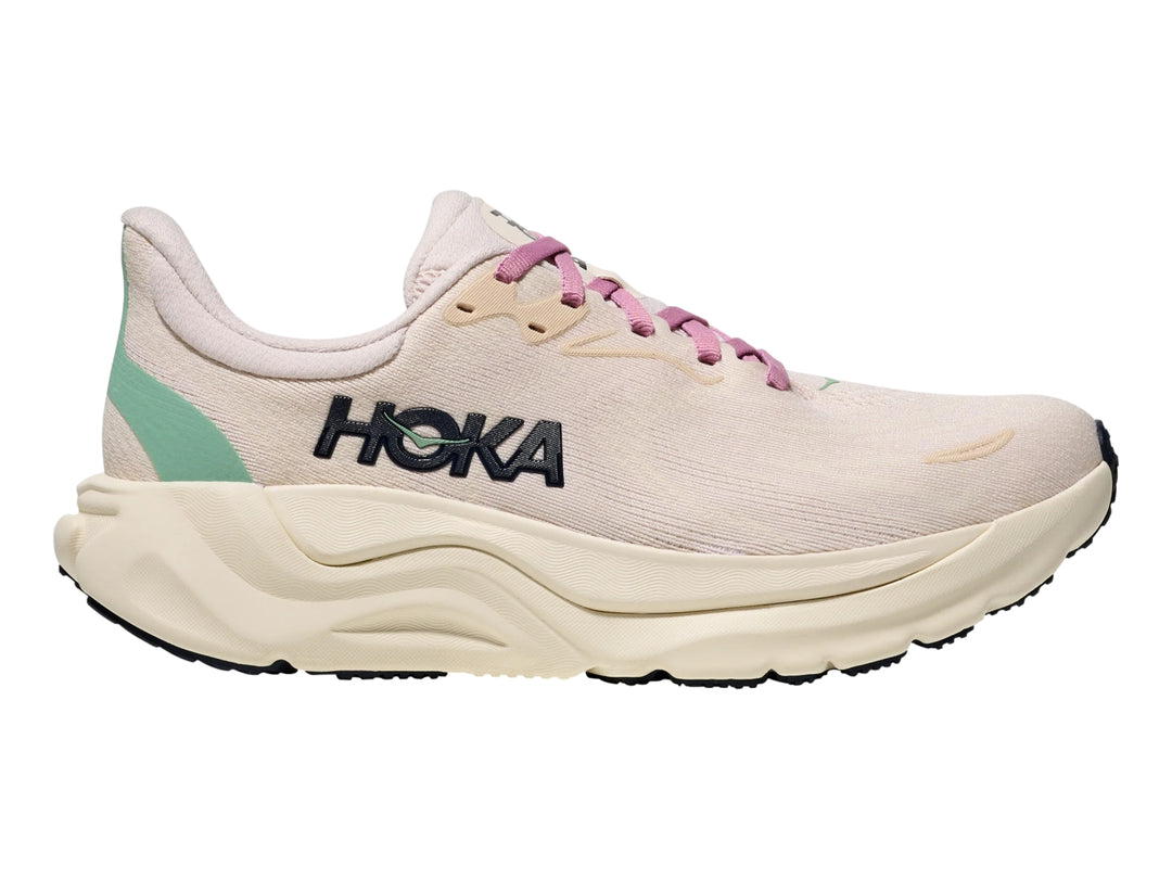 Tenis deportivos HOKA Arahi 8 en color rosa crema y blanco hueso con suela ancha y amortiguada.