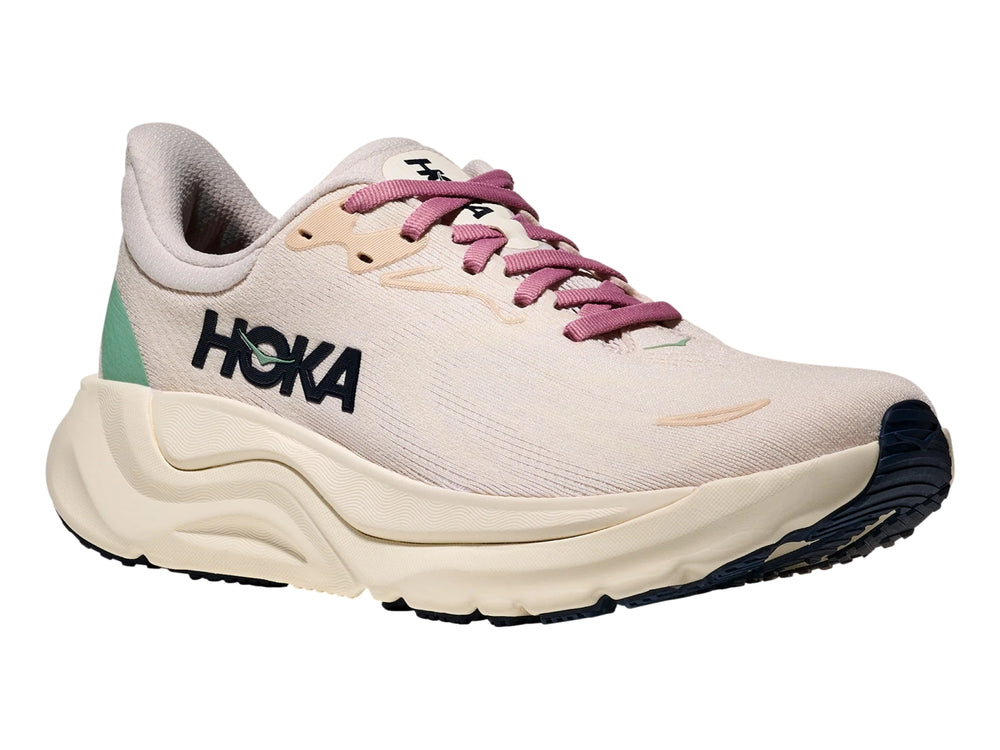 Tenis deportivos HOKA Arahi 8 en color rosa crema y blanco hueso con suela ancha y amortiguada.