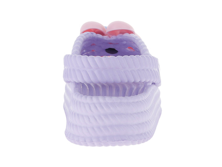 Sandalias tipo clog color lila para niña con adorno rosa en la parte superior.