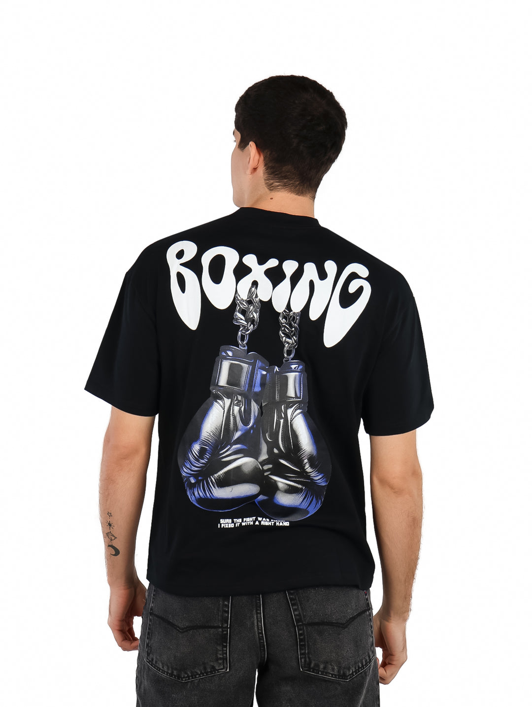 Hombre vistiendo playera oversize color negro con estampado blanco de la palabra BOXING en el pecho.